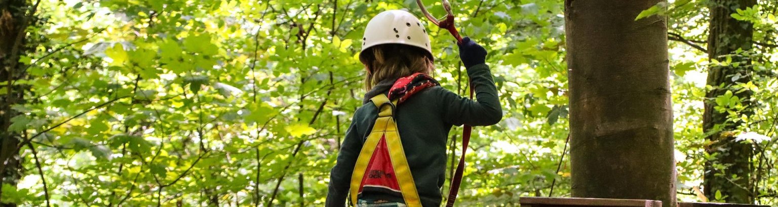 Kind das im Hochseilgarten klettert. 