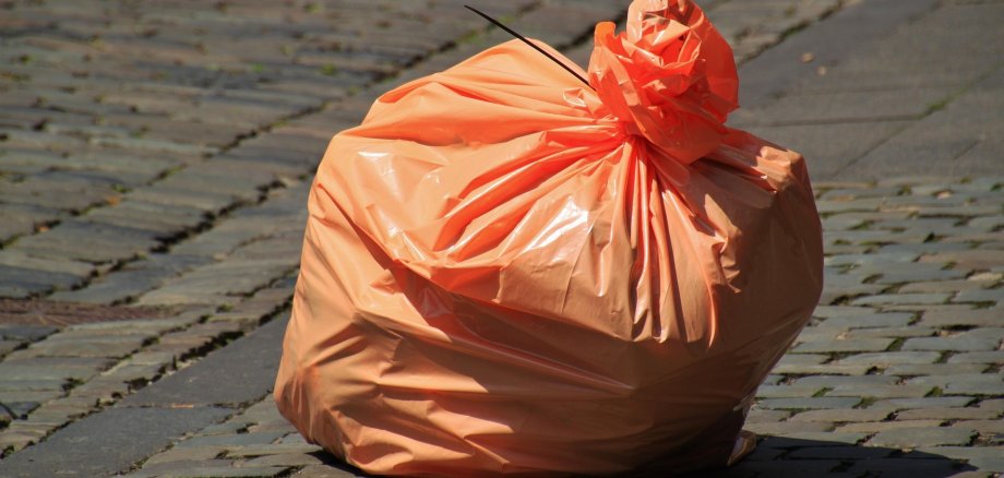 Müllbeute (orange) auf dem Asphalt