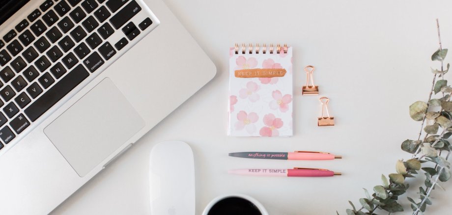 Laptop mit Notizblock, Kaffee und Stift